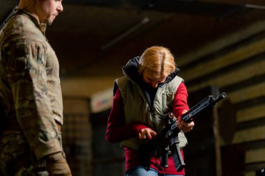 Profesyonel bir atış poligonunda askeri eğitmen, ucuz bir kıza NATO tüfeğini nasıl dolduracağını öğretiyor.