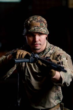 Profesyonel bir atış poligonunda bir askeri taktik eğitmeni elinde bir NATO tüfeğiyle duruyor.