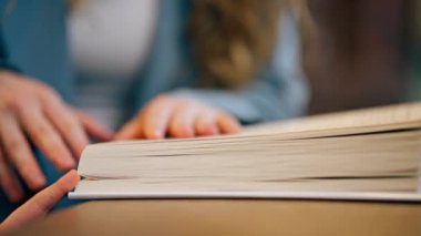 Pencerenin yanındaki kitapçıda oturan genç bir anne çocuğuna çocuk gelişimi okumayı öğretiyor.