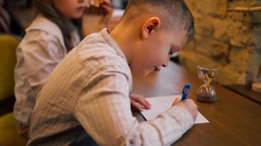 Kitapçıda yakın plan. Masada oturan yakışıklı bir çocuk matematik denklemlerini çözüyor.