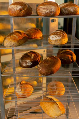 Profesyonel bir mutfakta, demir bir askıda taze pişmiş taze sıcak ekmek.