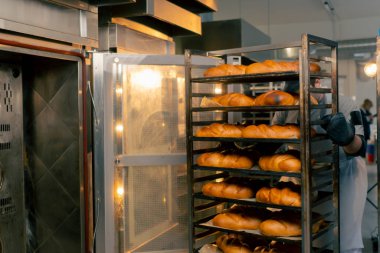 Profesyonel bir mutfakta, kapsayıcı bir fırıncı hazır ekmek rafı sergiler.