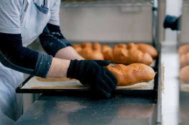 Profesyonel bir mutfakta yemek tepsisinden ekmek alan bir fırıncının yakın çekimi.