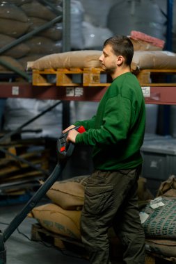 Kahve fabrikasında çalışan bir işçi makineyi kontrol etmek için forklift kontrol paneli kullanıyor.