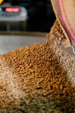 Bir kahve kızartıcı fabrikada yakın plan kahve poşetinden teraziye dökülüyor.