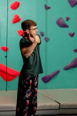 Tırmanma duvarında genç ve yakışıklı bir antrenör ısınma egzersizleri yapıyor.