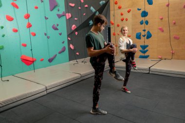 Kaya tırmanışı eğitiminden önce antrenörüyle tırmanan genç bir kız.