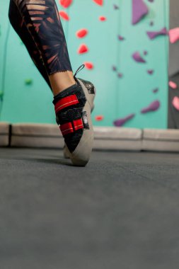 Profesyonel tırmanma ayakkabıları giyen bir kızın tırmanma duvarındaki bacakları.