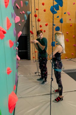 Tırmanma duvarında koç, antrenmandan önce kıza doğru tırmanma tekniğini gösterir.