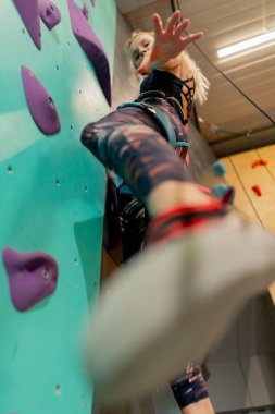 tırmanma duvarını kapatın genç bir kız ilk kez duvara tırmanıyor, koç emniyet halatıyla bağlanıyor.