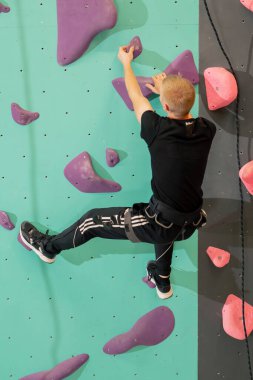 Tırmanma duvarında genç ve yakışıklı bir antrenör sigortası olmadan duvara tırmanıyor.