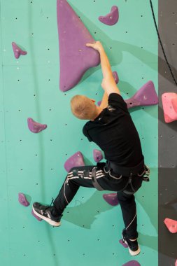 Tırmanma duvarında genç ve yakışıklı bir antrenör sigortası olmadan duvara tırmanıyor.