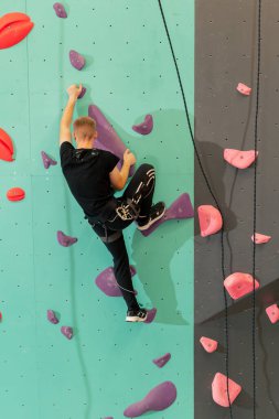 Tırmanma duvarında genç ve yakışıklı bir antrenör sigortası olmadan duvara tırmanıyor.