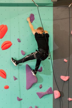 Tırmanma duvarında genç ve yakışıklı bir antrenör sigortası olmadan duvara tırmanıyor.