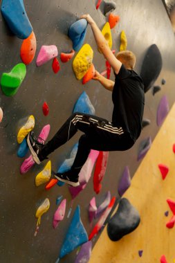 Tırmanma duvarına yakın çekim yapan genç, yakışıklı, profesyonel bir antrenör sigortası olmadan duvara tırmanır.