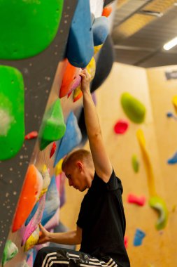 Tırmanma duvarına yakın çekim yapan genç, yakışıklı, profesyonel bir antrenör sigortası olmadan duvara tırmanır.