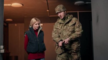 Profesyonel bir atış poligonunda bir asker bir kıza nasıl silah doldurulacağını anlatır ve gösterir.