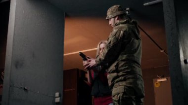 Profesyonel bir atış poligonunda bir asker bir kıza tabancayla doğru duruşu gösterir.