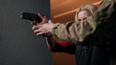 Profesyonel atış poligonunu kapatın. Bir asker bir kıza tabancayla doğru duruşu gösterir.