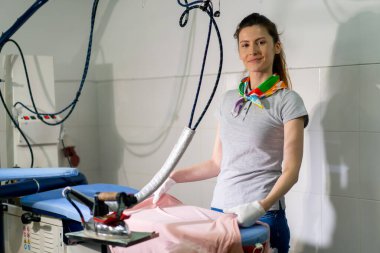 Profesyonel kuru temizlemeci kız kameraya profesyonel ekipman ütülemek için pembe bir ceket seriyor.