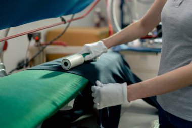 Profesyonel bir kuru temizlemeci. Genç bir kız, siyah ceketteki yünü çıkartmak için bir silindir kullanır.