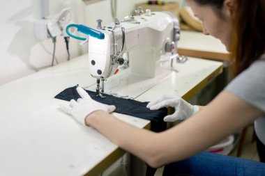 Profesyonel bir kuru temizlemeci. Genç bir kız dikiş makinesiyle süveterini parçalıyor.