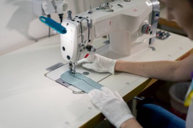 Profesyonel bir kuru temizlemeci. Genç bir kız dikiş makinesiyle süveterini parçalıyor.