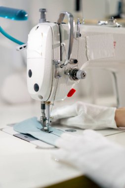 Profesyonel kuru temizlemeciyi kapat. Genç bir kız dikiş makinesiyle süveterini parçalıyor.