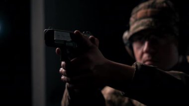 Profesyonel bir atış poligonu antrenörüne yakın çekim. Nişan alıyor ve ateş ediyor.