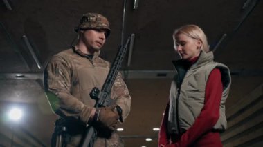Profesyonel bir atış poligonunda bir askeri eğitmen bir kıza NATO silahlarını nasıl kullanacağını söyler.