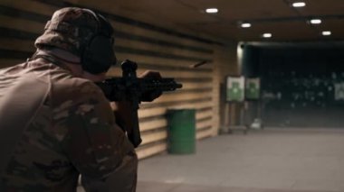 Profesyonel bir atış poligonunda cephaneli bir asker bir NATO tüfeğinden ateş eder.