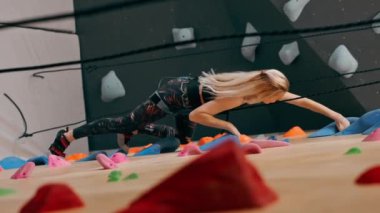 tırmanma duvarındaki dikey videoda genç bir kız emniyet ipinden aşağı iniyor, koç düşmeye karşı sigorta yaptırıyor.