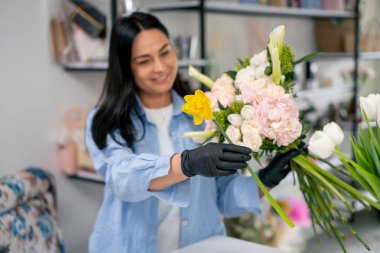 Çiçekçi bir kız beyaz bir masanın yanında güzel bir buket beyaz çiçek topluyor.