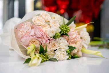 Beyaz bir masanın üzerindeki çiçekçide, sevdiğine hediye olarak hazır pembe bir buket duruyor.