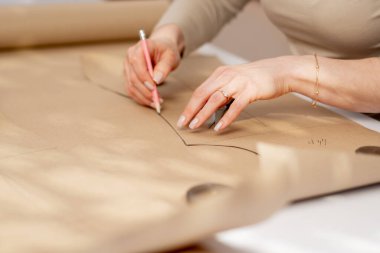 Profesyonel bir terzi, bir elbise için gelecekte desenler çizmek için kraft kağıdıyla çalışır.