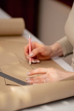 Profesyonel bir terzi, bir elbise için gelecekte desenler çizmek için kraft kağıdıyla çalışır.