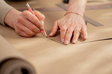 Profesyonel bir terzi, bir elbise için gelecekte desenler çizmek için kraft kağıdıyla çalışır.