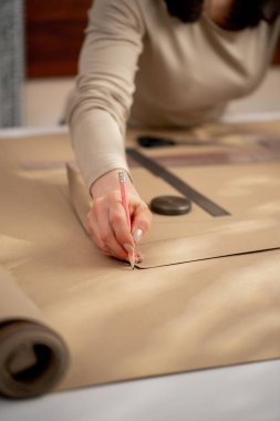 Profesyonel bir terzi, bir elbise için gelecekte desenler çizmek için kraft kağıdıyla çalışır.