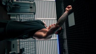 Spor salonunda siyah tişörtlü yakışıklı genç adam egzersiz makinesinin önünde ısınma egzersizi yapıyor.