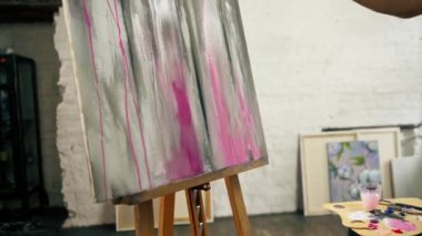 Bir sanat atölyesinde, tuvaldeki fırçayla pembe lekeler yaratırken.