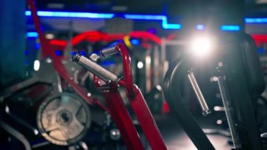 Spor salonunda alacakaranlıkta kasları çalıştırmak için egzersiz makineleri var kırmızı metal.