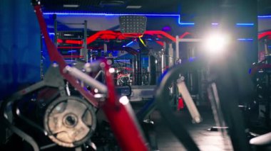 Spor salonunda alacakaranlıkta kasları çalıştırmak için egzersiz makineleri var kırmızı metal.