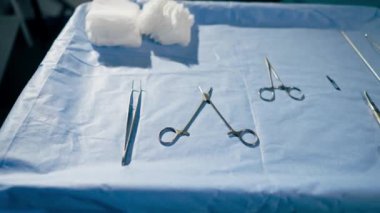 Ameliyat masasında mavi arka planda ameliyat yapmak için cerrahi aletler var.