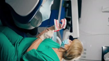 Bir dişçi kliniğinde dişçiye dişlerini nasıl fırçalayacağını gösterir.