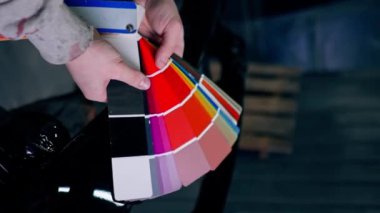 Bir servis istasyonunda el ele çekilmiş dikey video. Usta bir renk paleti üzerinde bir boya rengi seçer.