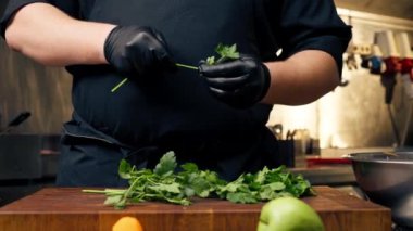 Profesyonel bir mutfağa yakın plan masa şefi maydanozu kökünden soyar.