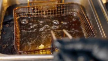 Profesyonel bir mutfakta yakın plan çekimde kızartma kızartmasını fritözde yağda kızartıyorum.