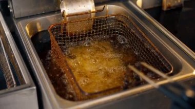 Profesyonel bir mutfakta yakın plan çekimde kızartma kızartmasını fritözde yağda kızartıyorum.