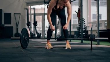 Spor salonunda bir kız antrenör halterle zıplarken yerde zıplar.