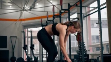 Spor salonunda bir kız antrenör halterle zıplarken yerde zıplar.